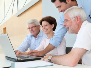 a group of people sitting around a laptop computer.