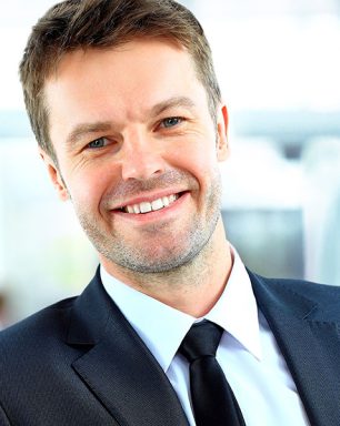 a man in a suit and tie smiling at the camera.